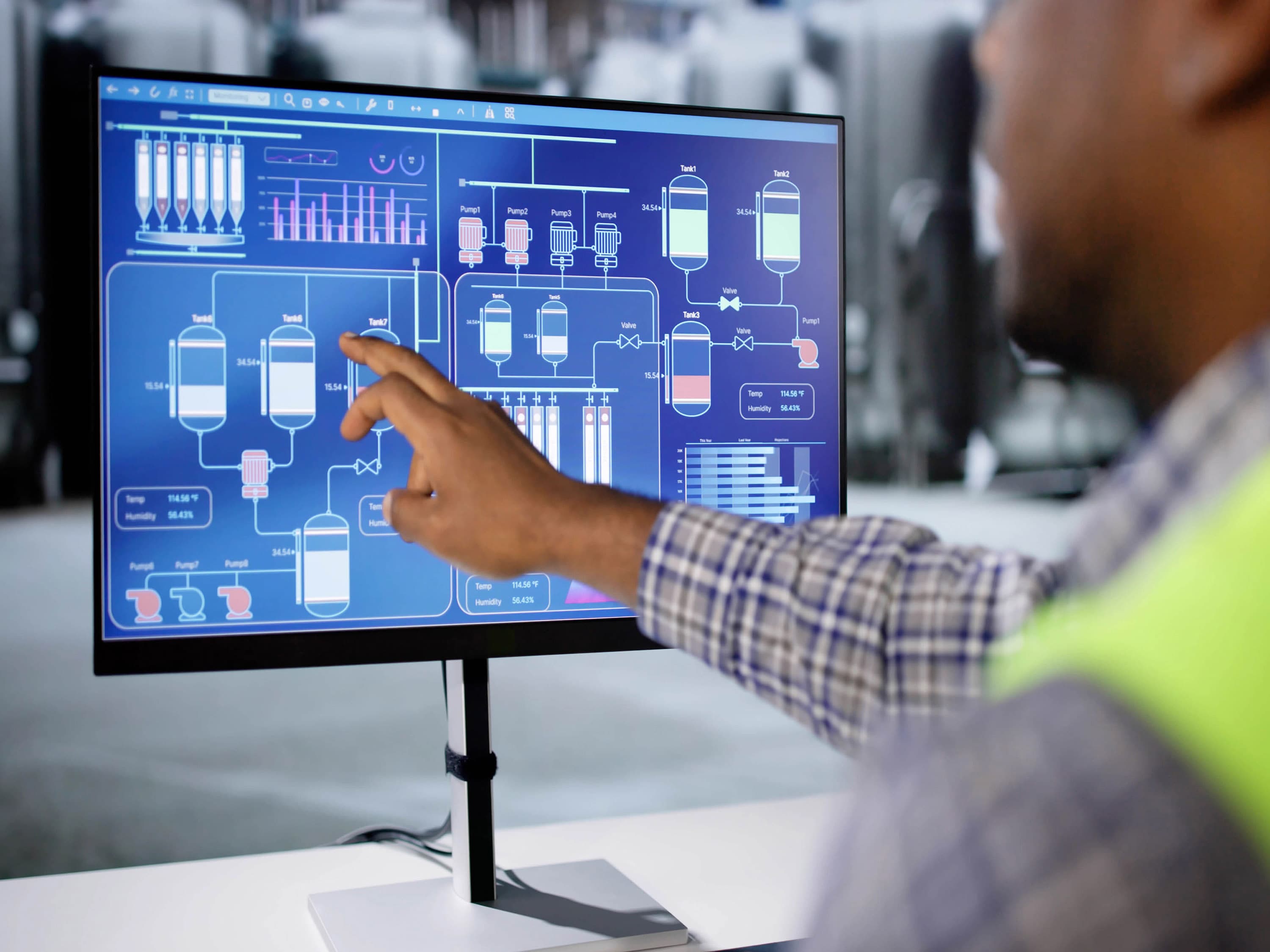 Man pointing at a PC monitor showing the planning of a plant