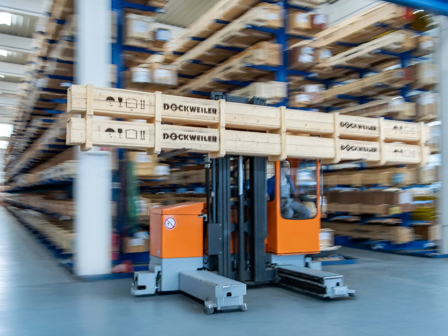 Forklift has loaded a box and is standing in front of a rack storage area with boxes