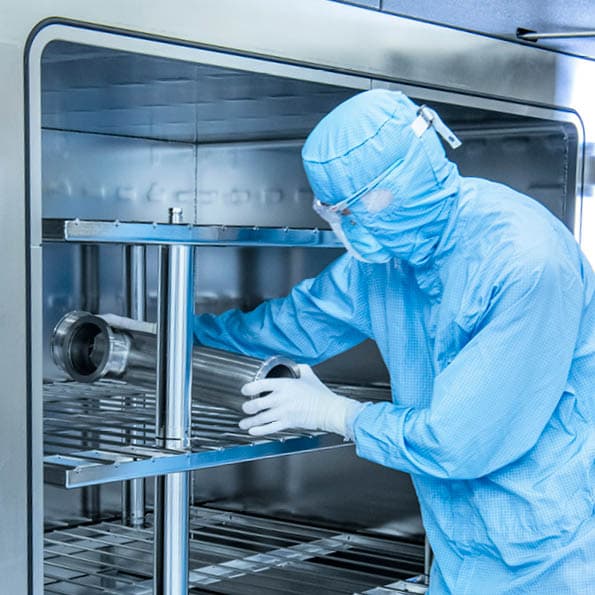 Person in cleanroom clothing places components in the machine to perform RGA measurement