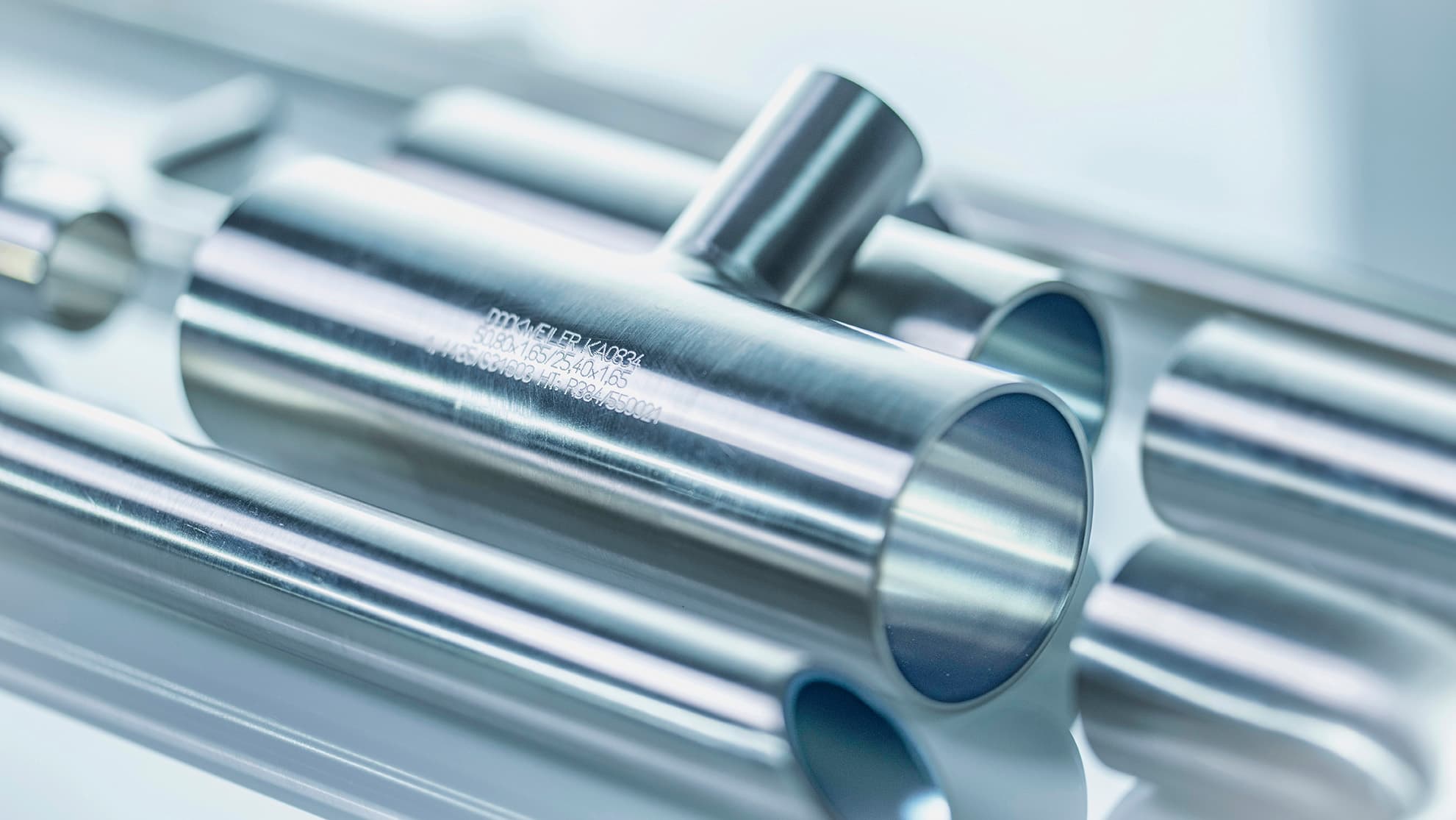 Close-up of polished stainless steel tubes with engraved markings, showcasing precision and industrial quality.