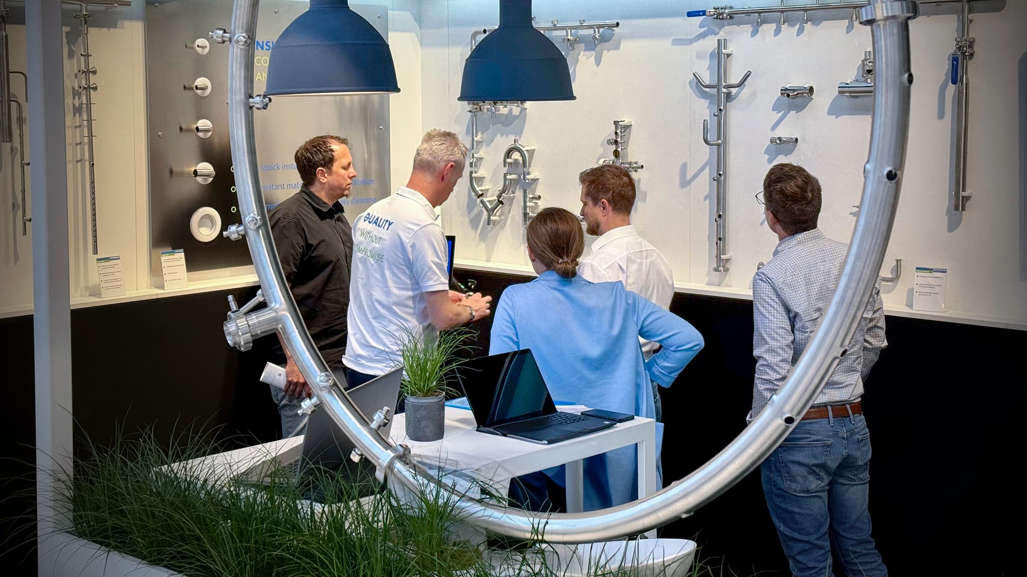Dockweiler Expert talking to exhibiron visitors in front of a wall with stainless steel components