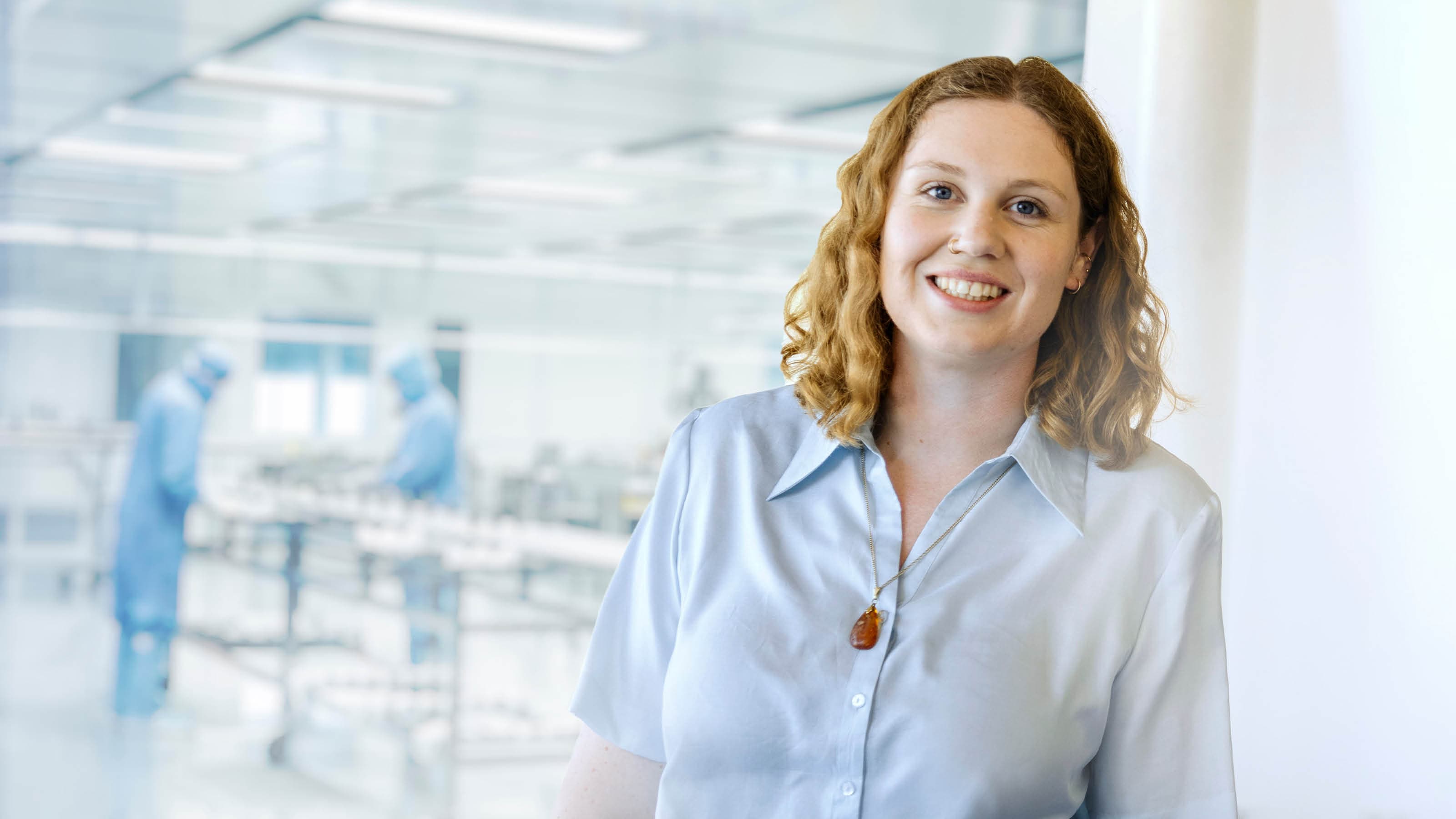 Woman standing in front of a clean room where employees are working