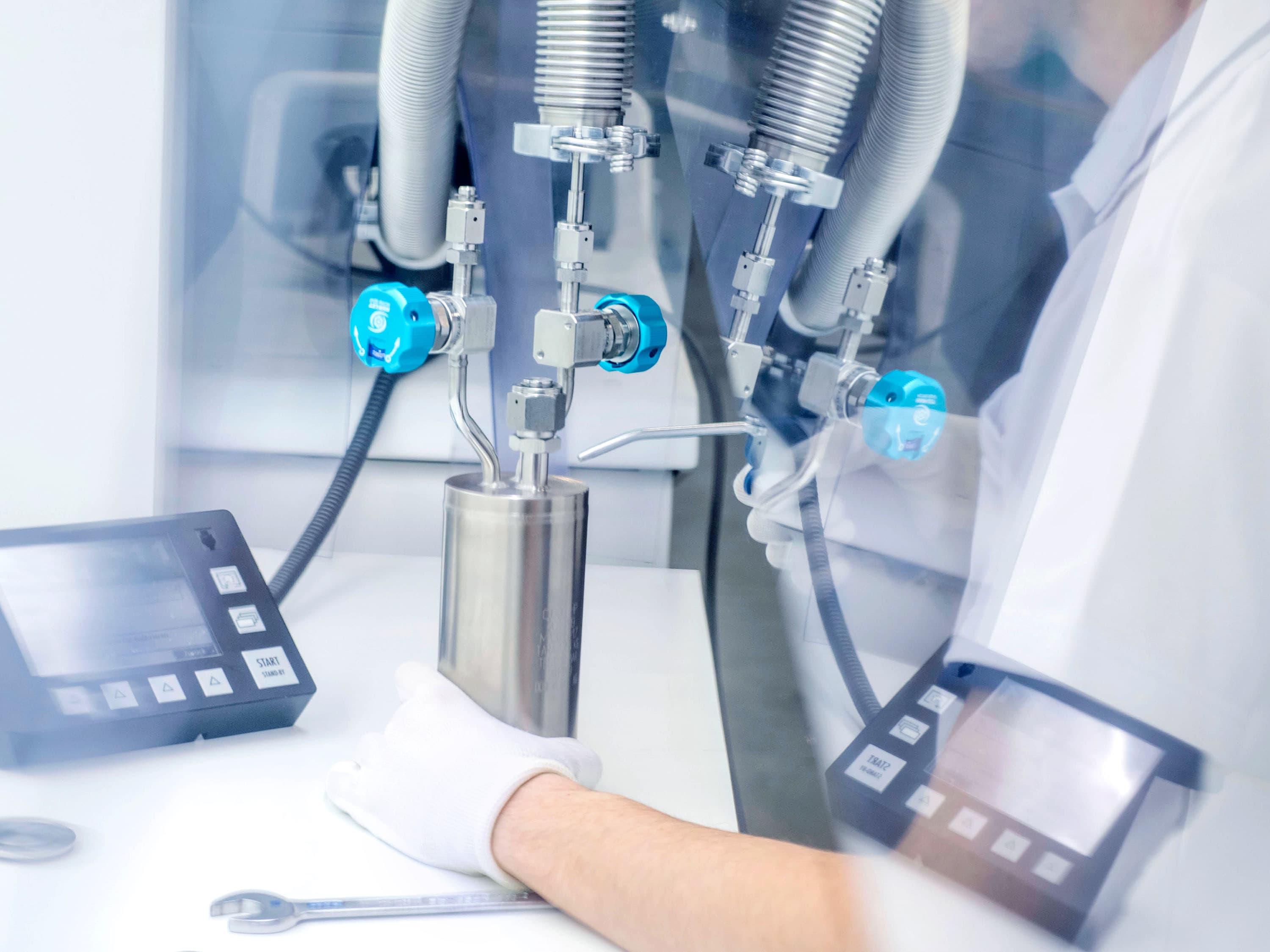 Person wearing white cleanroom gloves performing a helium leak test on a process vessel