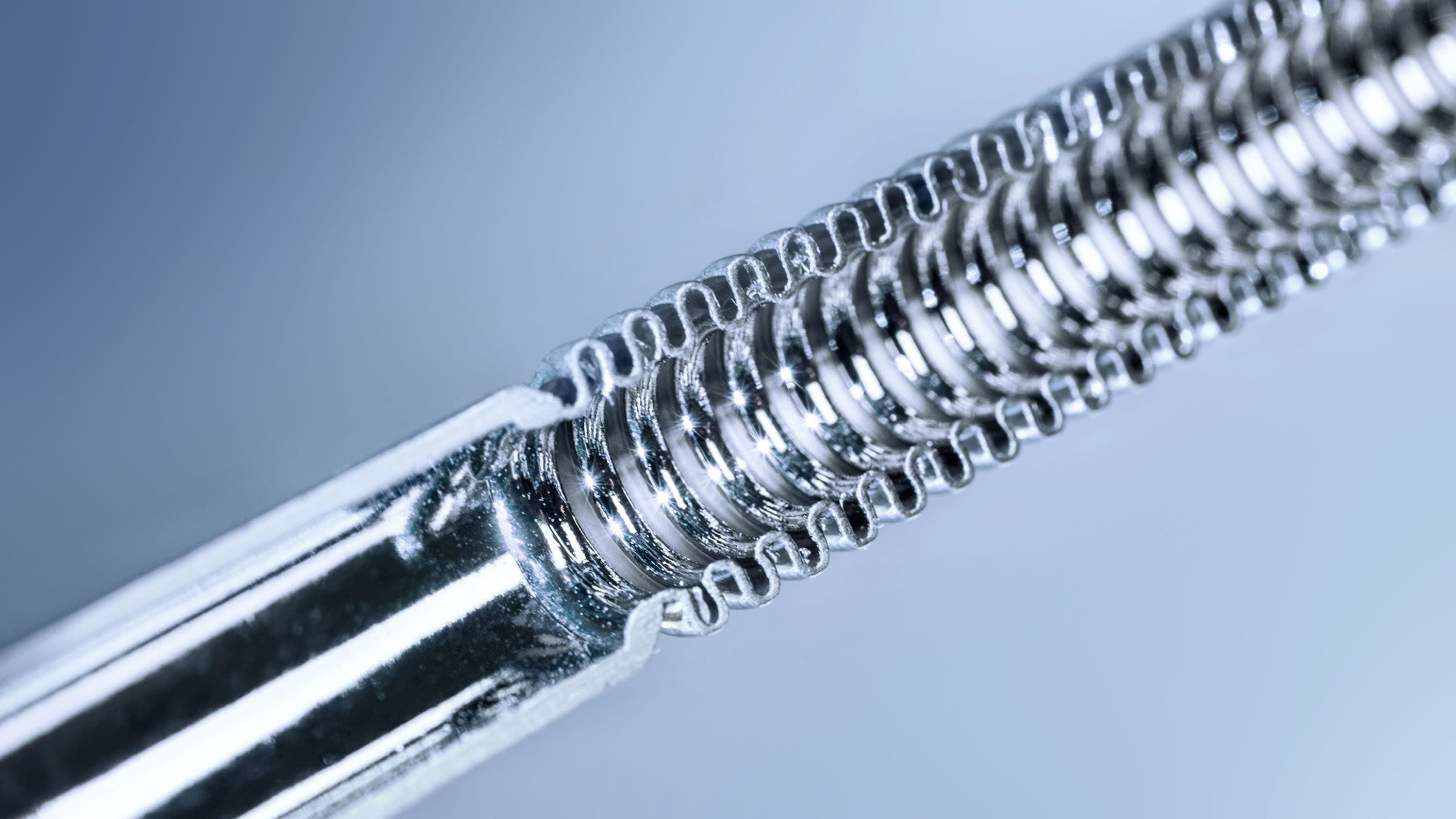 Corrugated stainless steel hose half cutted on light blue background