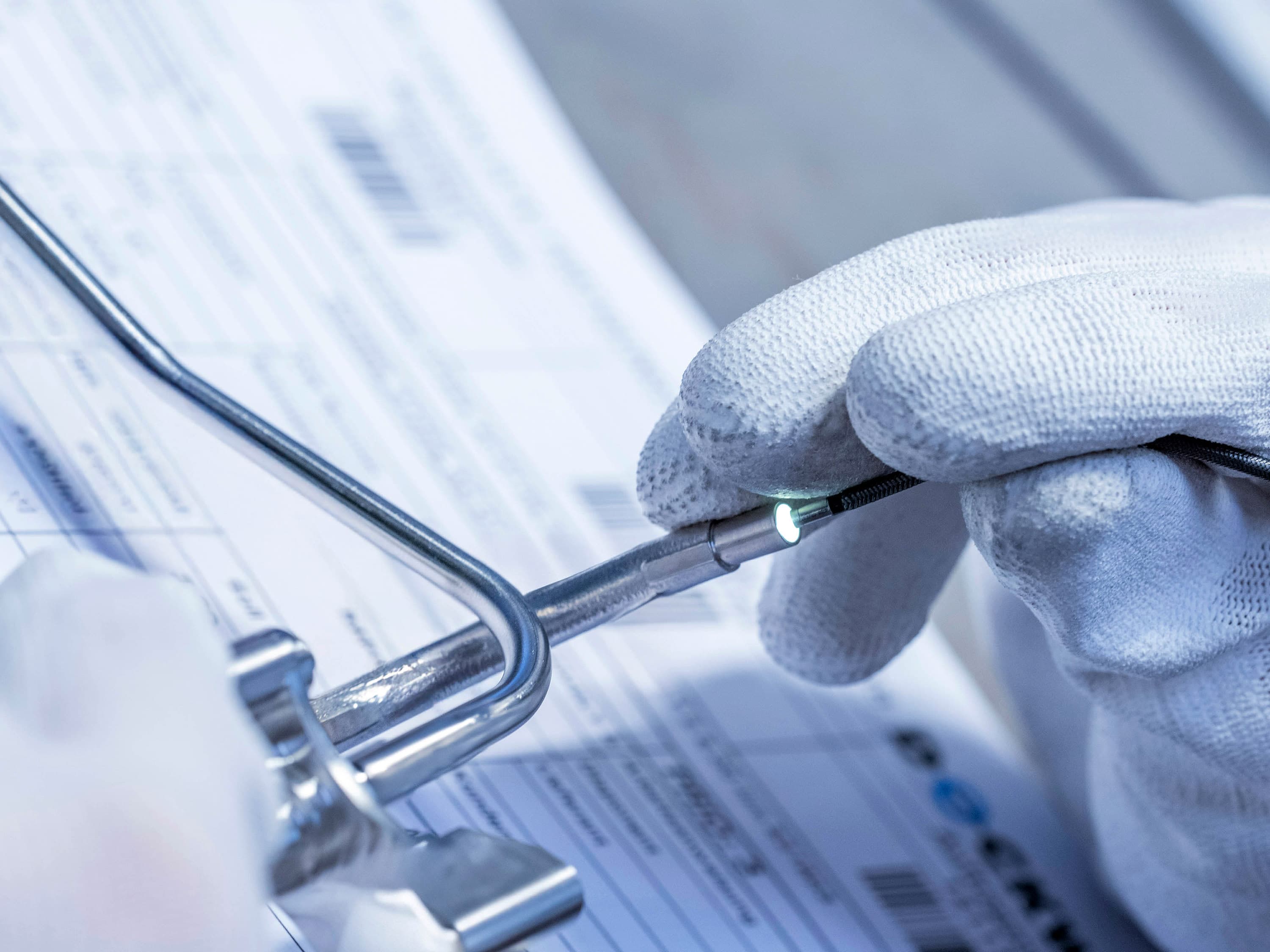 Hands in white gloves are endoscoping a stainless steel component.