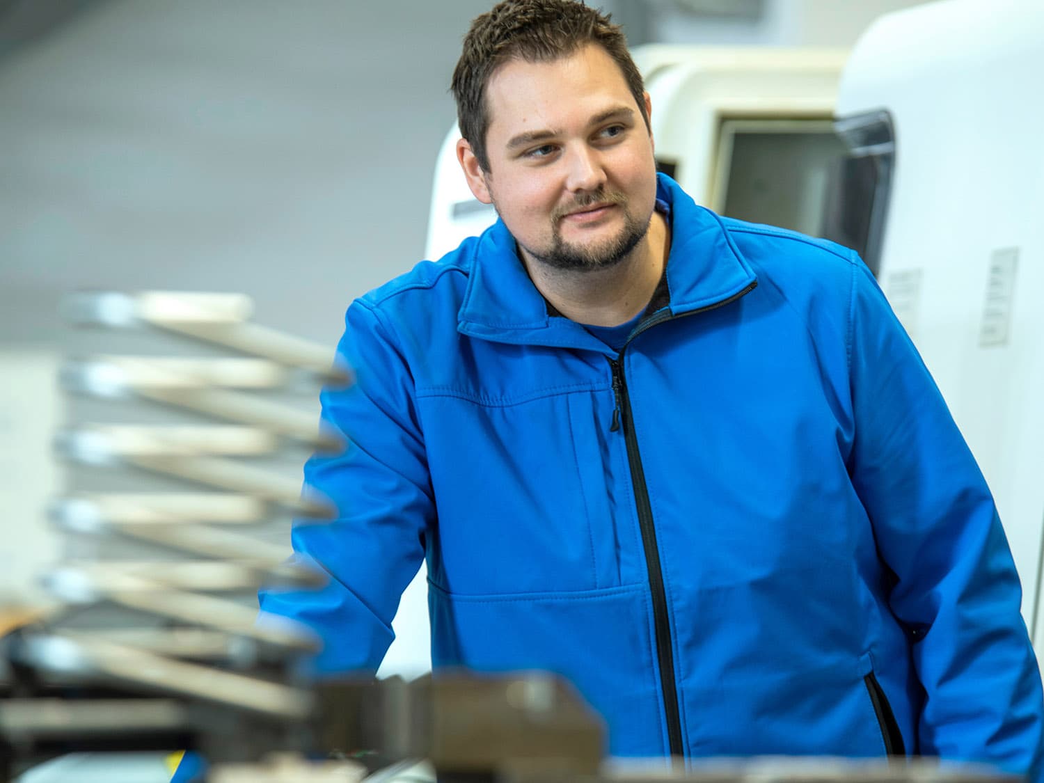 Man in blue jacket behind a stainless steel component in the production