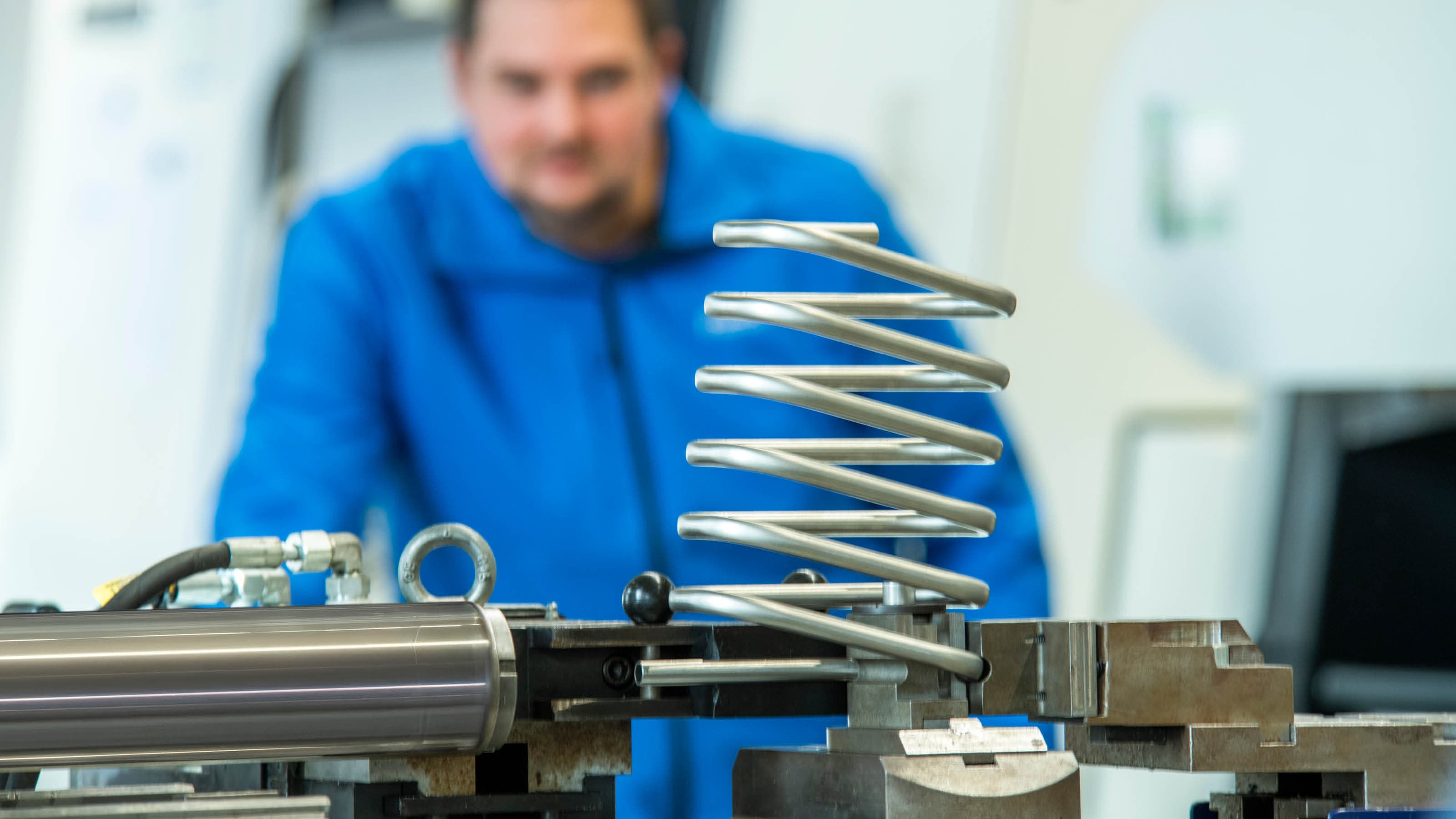 Curved stainless steel tube system in a production environment; an employee can be seen out of focus in the background