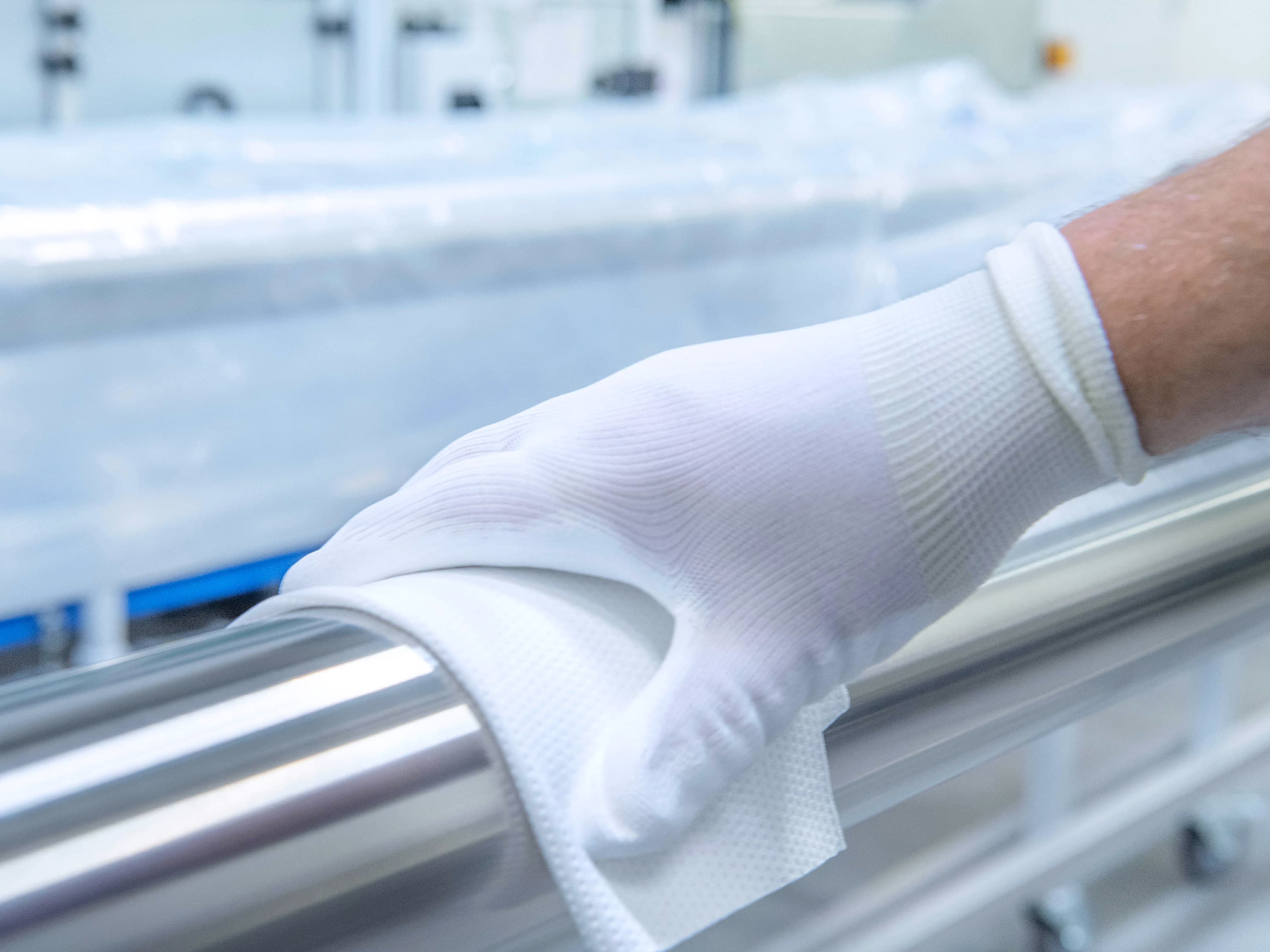 Hand with white glove wiping a tube from the outside
