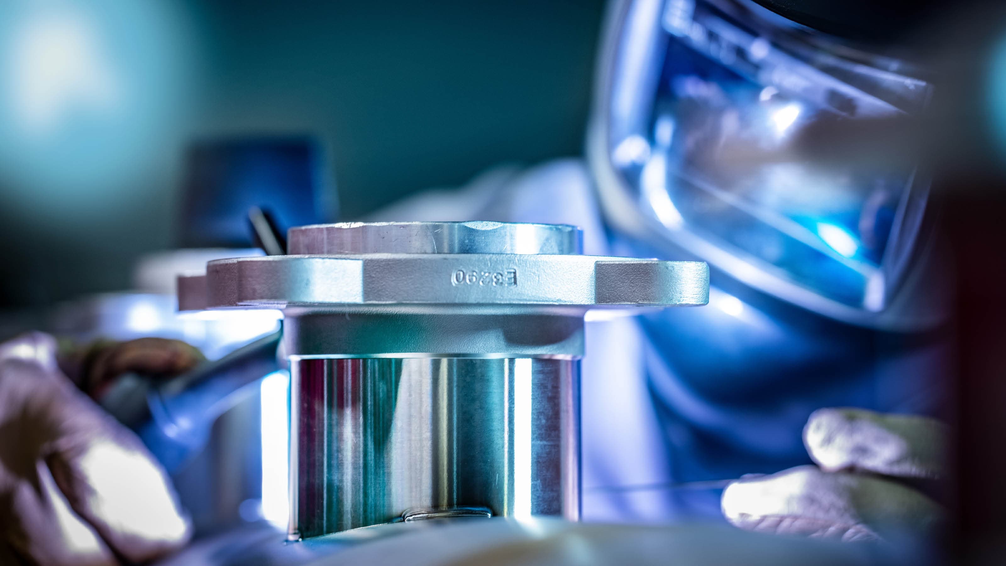 Welder wearing a helmet and protective clothing welds a stainless steel component by hand